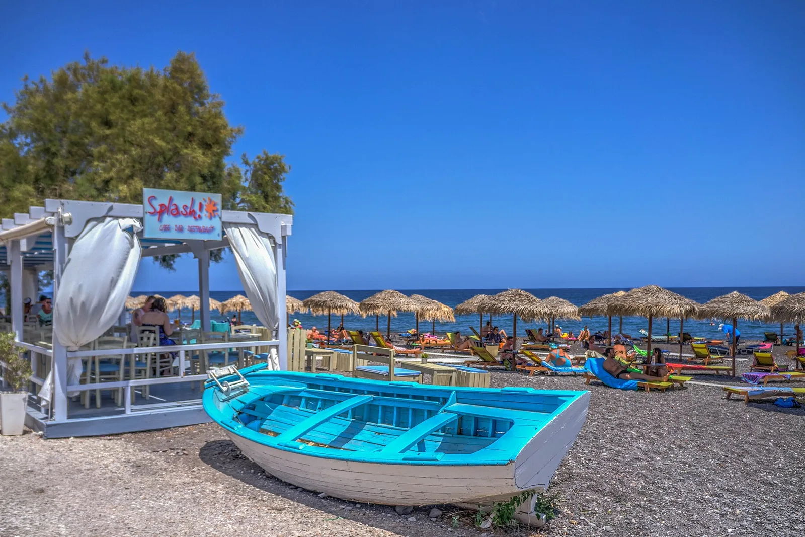 Sunbeds and a painted fishing boat on Kamari beach, Santorini
